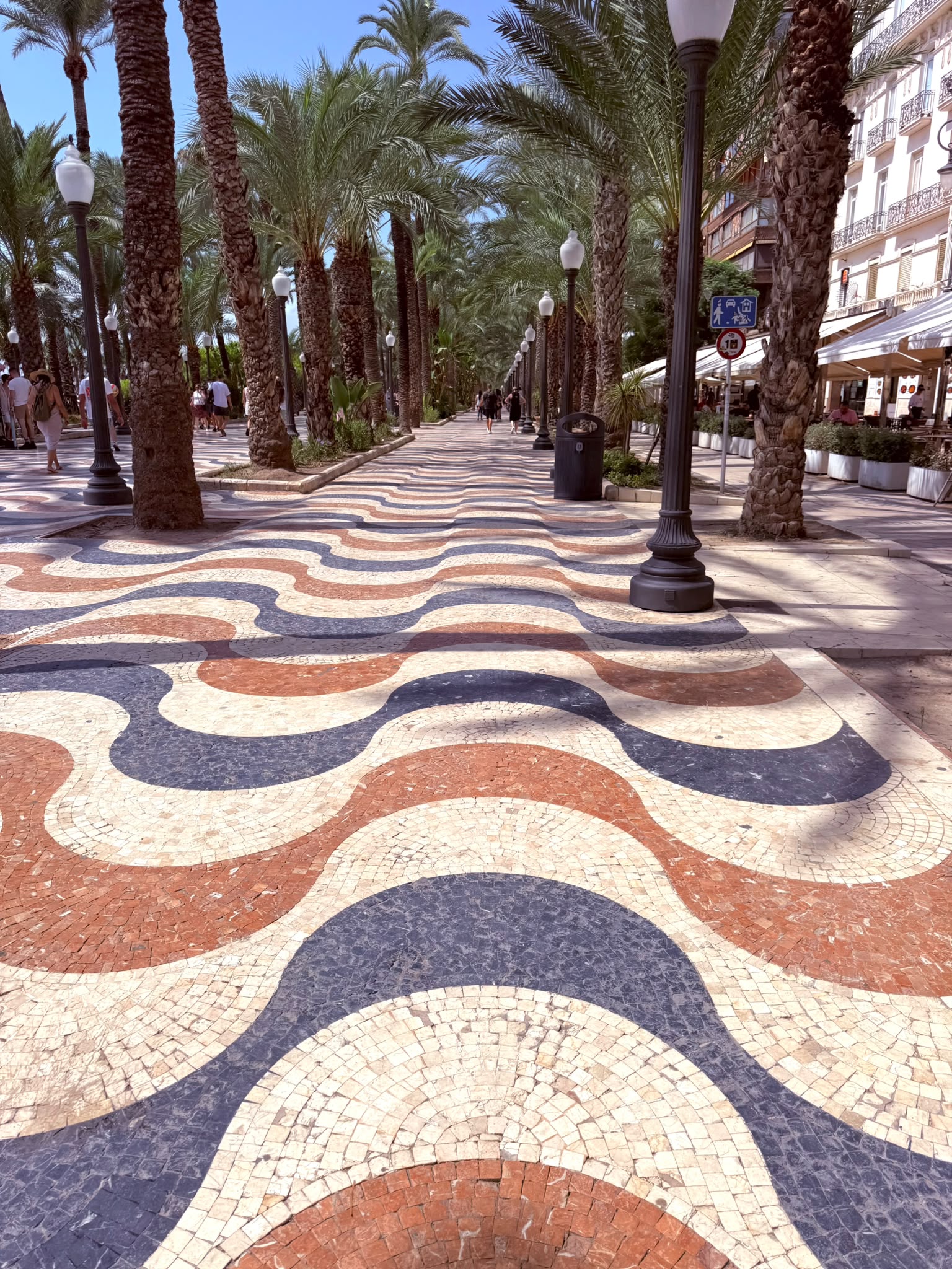 Pavajul ondulat din marmură al promenadei Explanada din Alicante, mărginită de palmieri